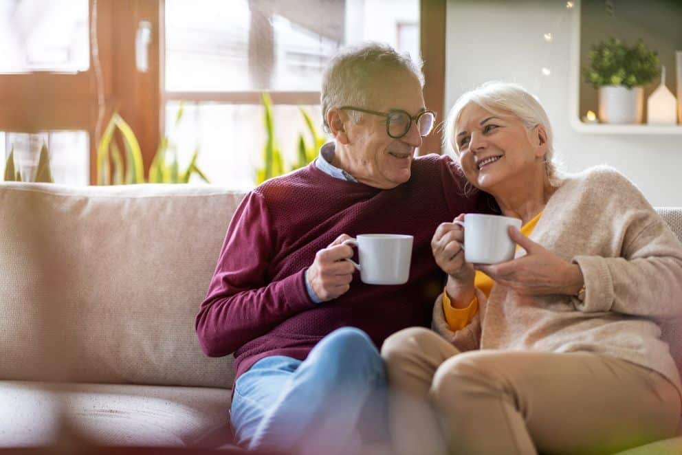 A senior couple on a couch enjoying a cup of coffee