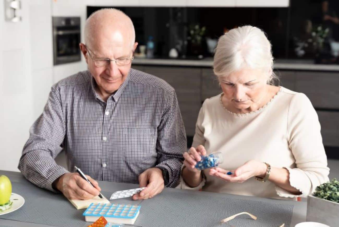 A senior man and a senior woman plan their medication for the week A senior man and a senior woman plan their medication for the week