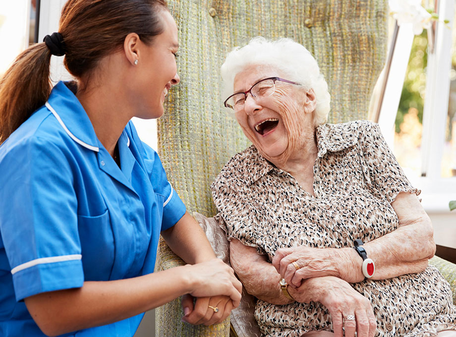 A senior woman smiles and laughs with a health care professional