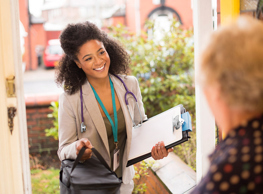 A health care professional delivering something to a senior's home