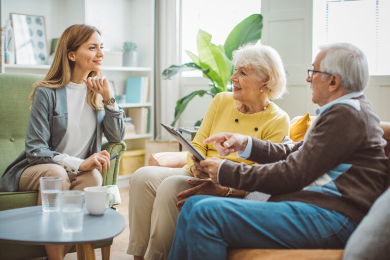 Senior couple talking with female financial or real estate advisor at home.