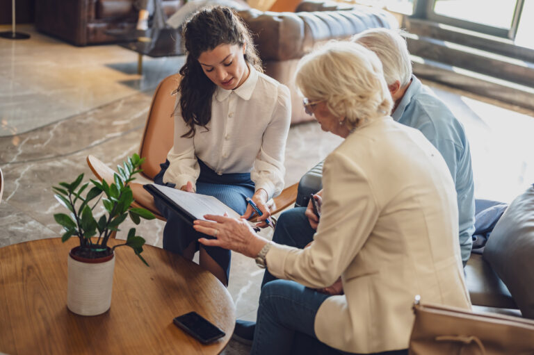 A hotel or travel agency representative is talking with a senior tourist couple offering various tourist services