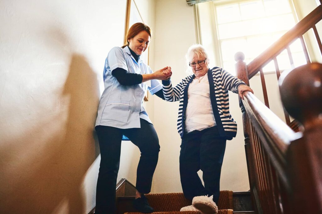 nurse helping senior down stairs