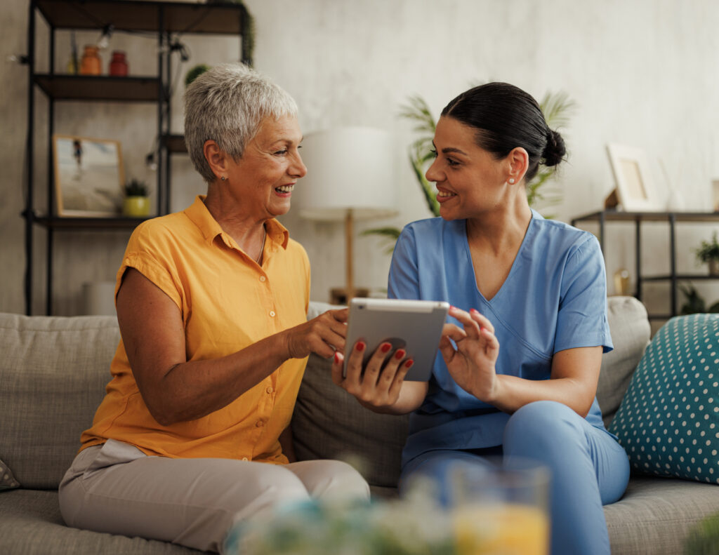 Nurse and older woman discussing something while looking at a tablet