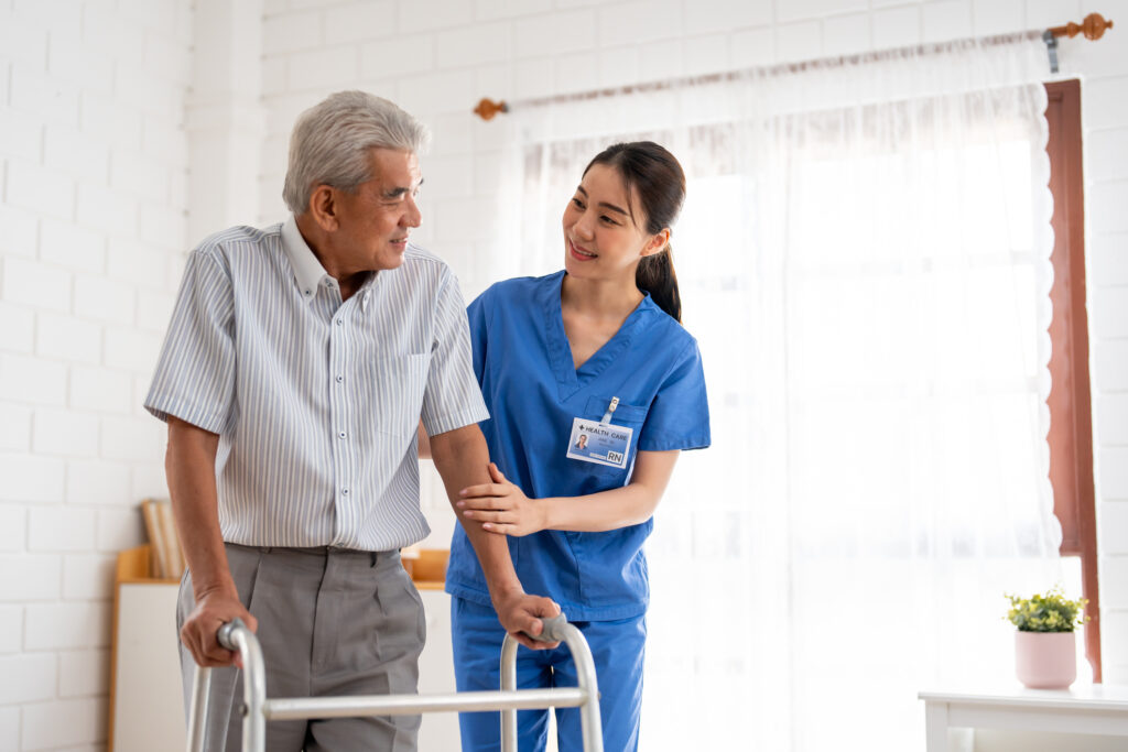 Asian senior older woman patient doing physical therapy with caregiver. Attractive specialist carer women help and support elder mature female practice walking slowly with walker at nursing home care.