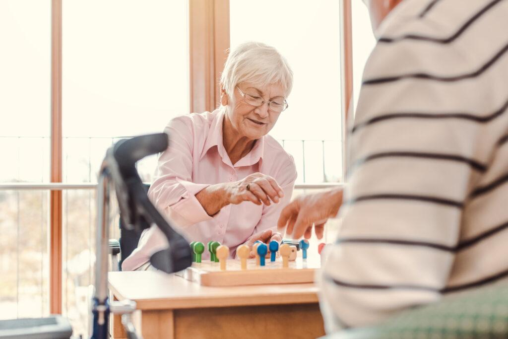 Two seniors, man and woman, in a nursing home playing a board game