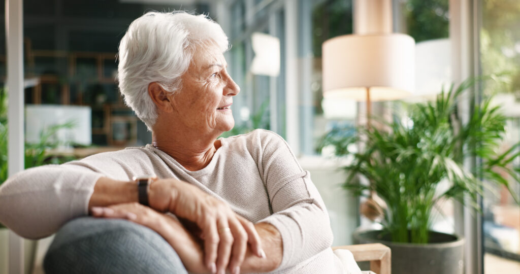 Elderly woman, smile and thinking in home for nostalgia, remember memory or past decision with vision. Thoughts, senior person and daydreaming on sofa with optimism, reflection or retirement plan