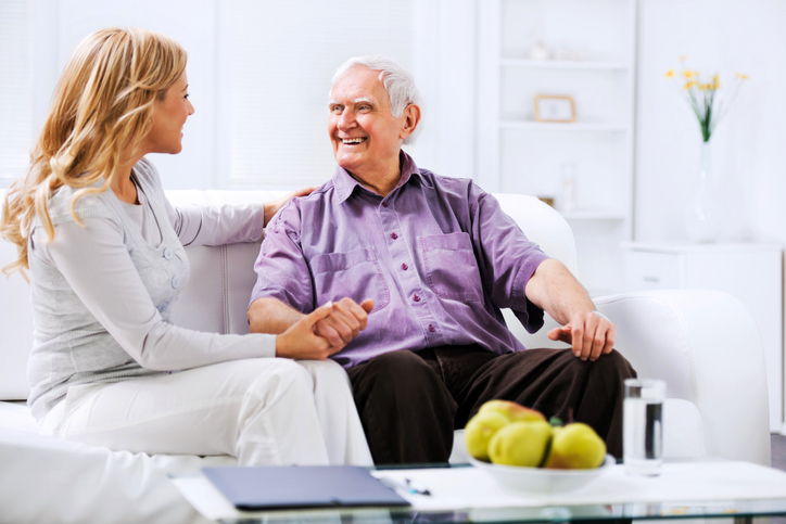 A caregiver sits with an older adult man during respite care