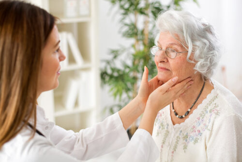 young doctor examining senior woman lymph glands