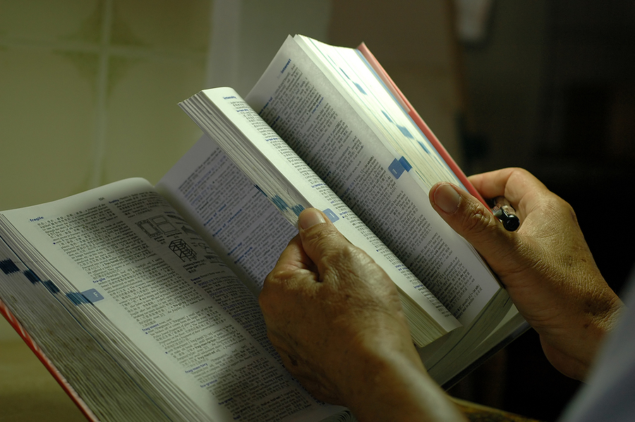 Senior hands are holding and sorting through a dictionary