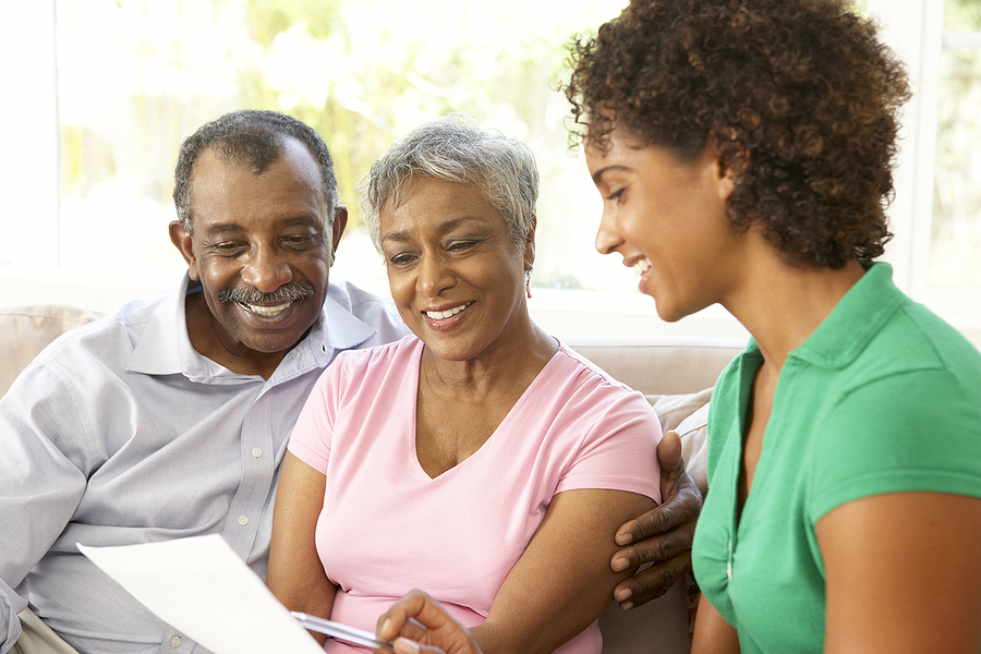 An adult woman talks with her senior parents in a living room