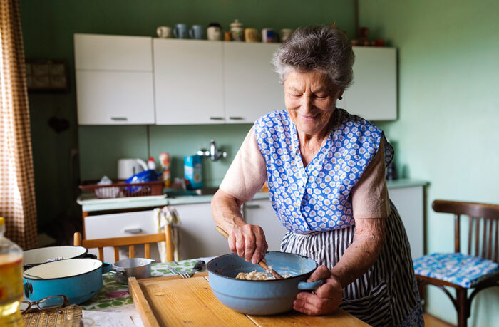 A senior woman using a mixing bowl to mix dough