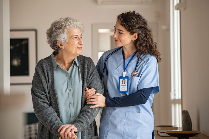 Senior woman walking in a room with a nurse
