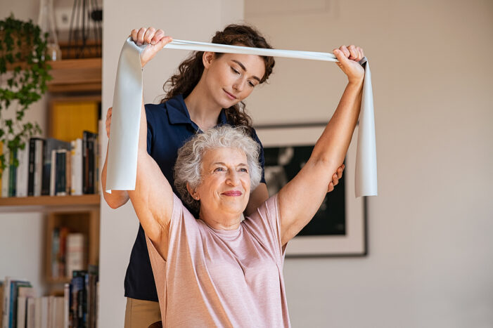 Senior woman doing a rehabilitation exercise with a caregiver