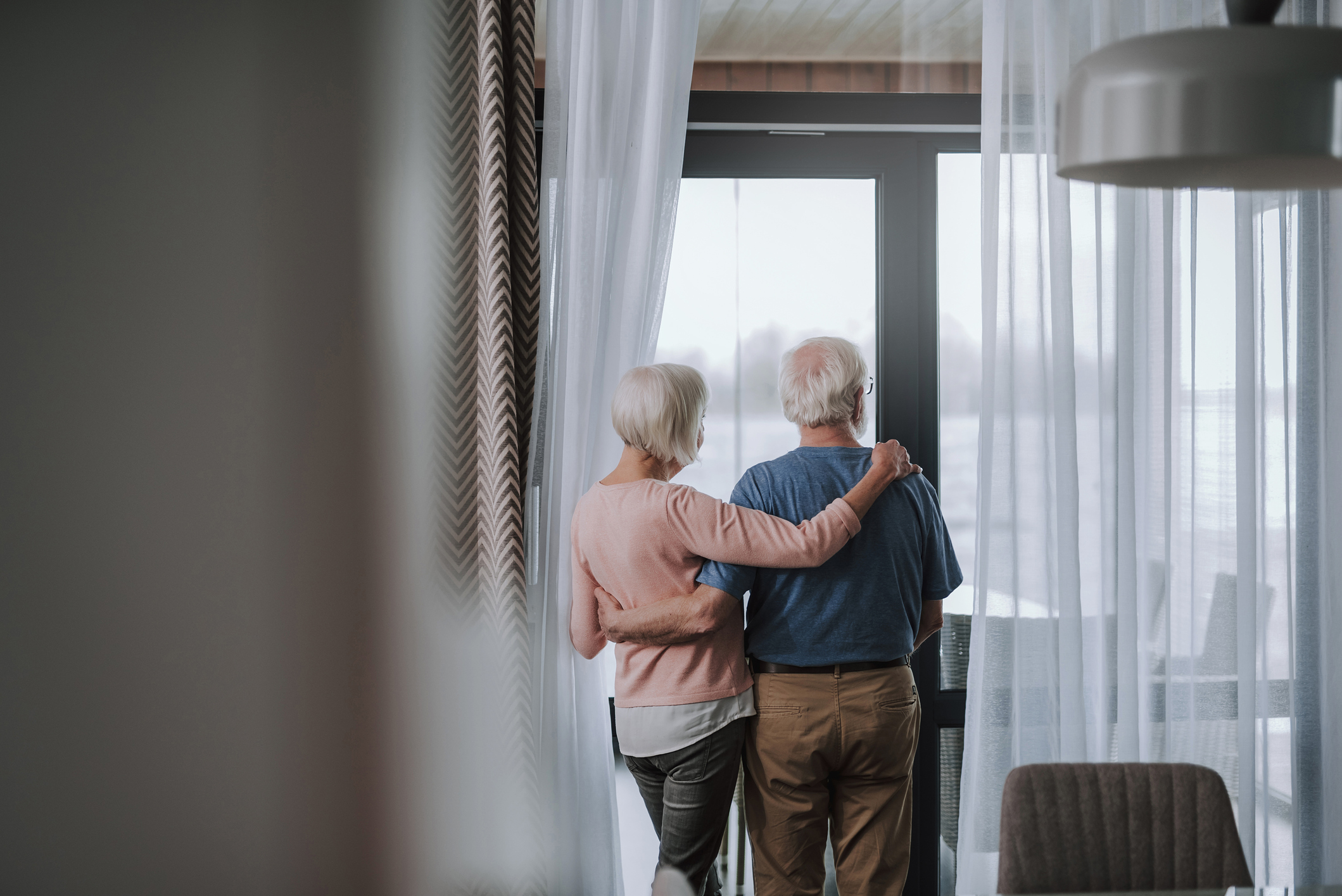 An older adult couple hugs during a senior apartment viewing