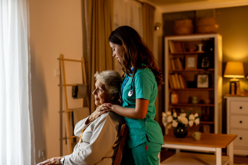 An empathetic healthcare worker comforts an elderly patient in a warm and inviting interior environment, symbolizing compassion, professional support, and the importance of personal connection in caregiving settings.